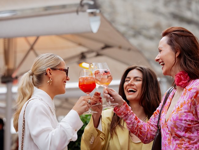 Drei Damen genießen Lillet‑Drinks beim Summer Opening mit sommerlichem Beach‑Flair
